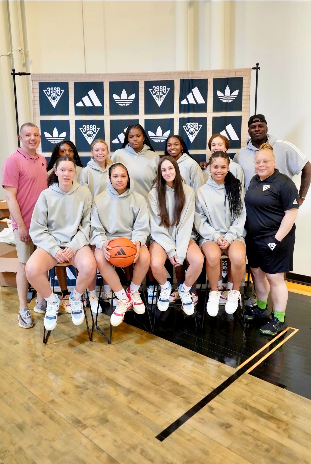 Lady Phenom United players and coaches in front of the Adidas 3SSB backdrop