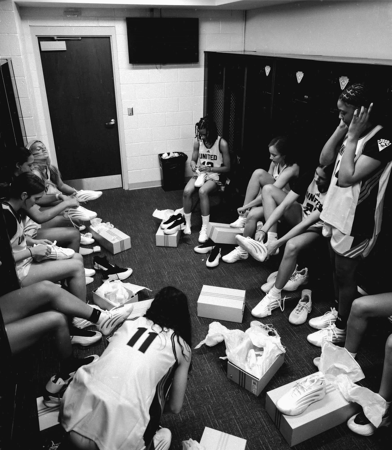 Lady Phenom United players in a locker room opening new team shoes together